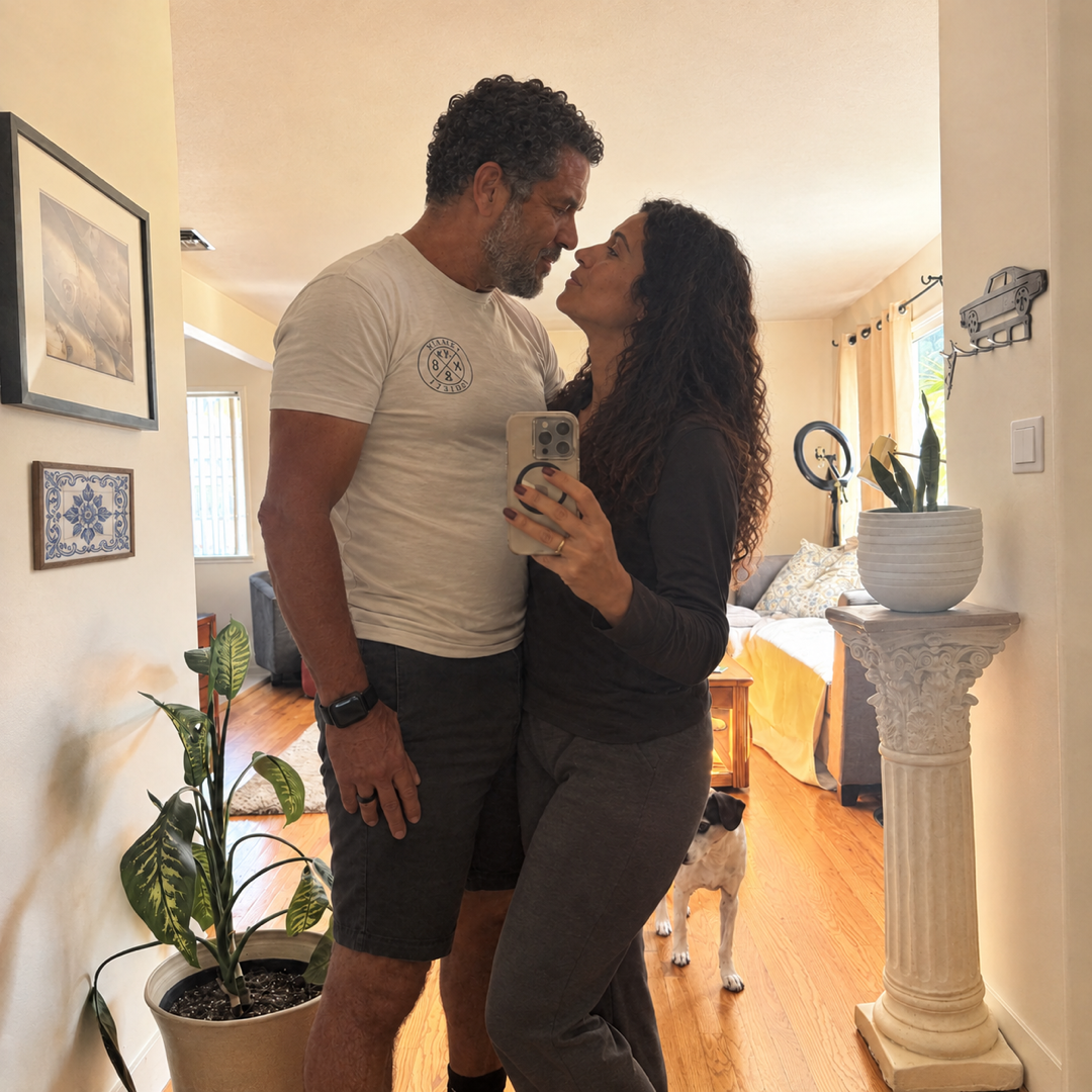 Casal a tirar uma fotografia ao espelho, com um cão ao fundo.